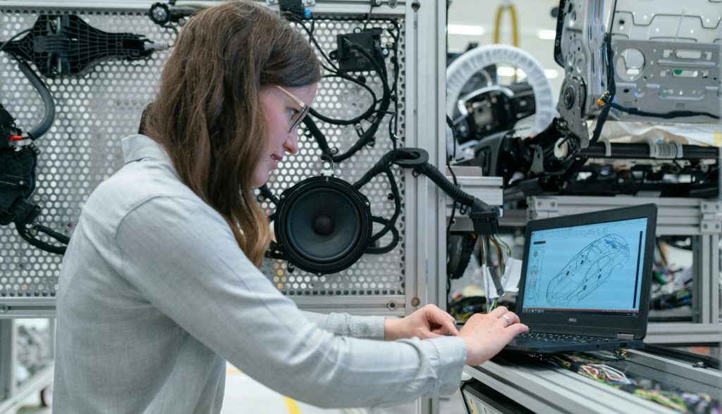 Woman working on laptop at modern factory workstation desk.