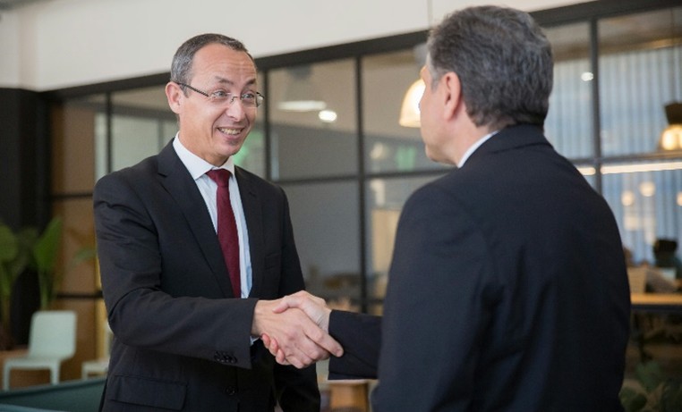 Scientist with gloves transferring liquid into beaker in lab.