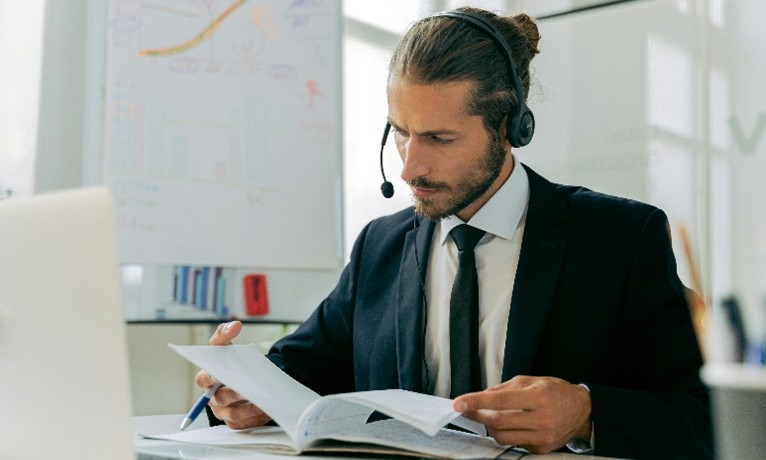 Professional with headset reviewing documents at office desk.